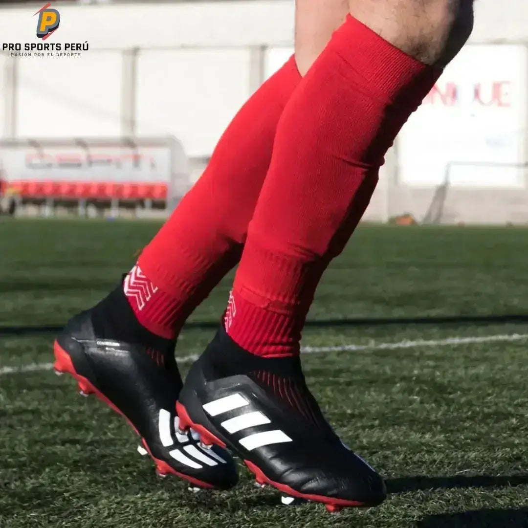 Jugador de fútbol usando medias deportivas rojas sin pie ProSocks sobre el campo con chimpunes.