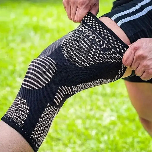 Persona acomodando la rodillera elástica con infusión de cobre sobre la rodilla para entrenar al aire libre.